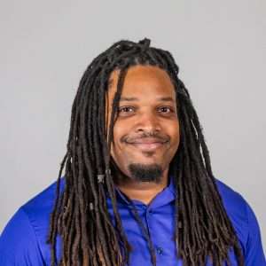 Headshot of Emmanual Eubanks (man with brown hair and blue shirt)