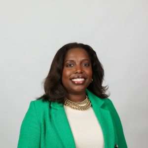 smiling woman with brown hair green blazer blank background