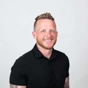 man smiling wearing black shirt in front of blank background