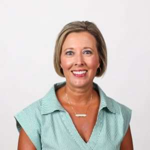 woman smiling wearing green and white stripe shirt in front of blank background