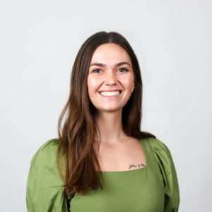 woman smiling wearing green shirt in front of blank background