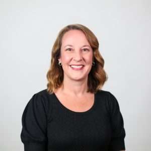 woman smiling wearing black shirt in front of blank background