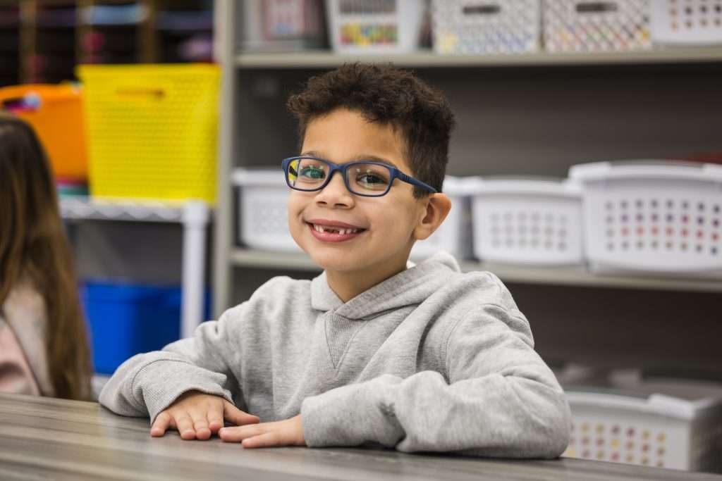 kindergarten boy at desk wearing glasses