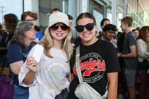two female students with a gift card wearing sunglasses