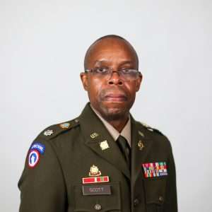 man wearing glasses and military uniform in front of blank background