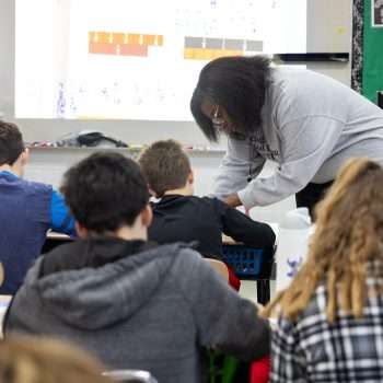 teacher leaning over desk helping a student