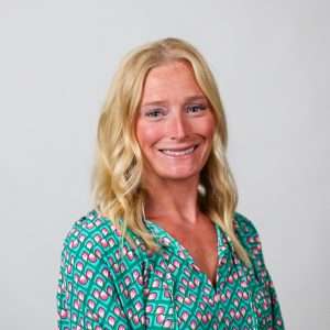 woman in colorful top smiling in front of blank background