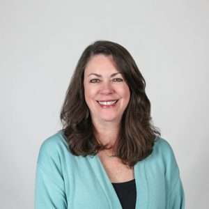 woman with brown hair wearing a blue cardigan
