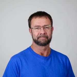 Brown hair man with blue shirt and glasses
