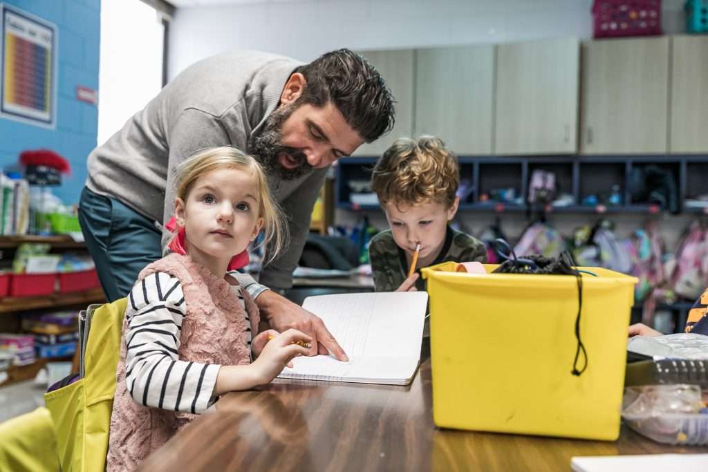 Two young students being helped by a male teacher