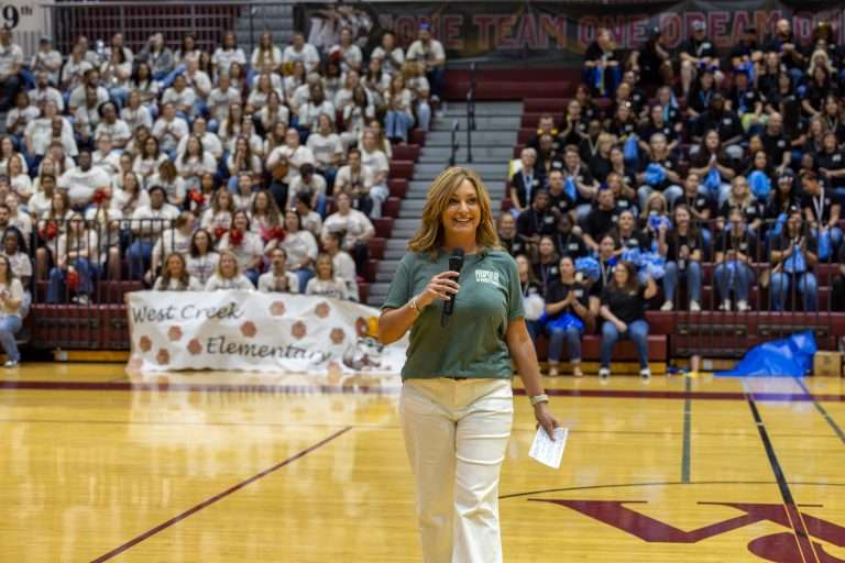 Blond woman standing in gym with microphone