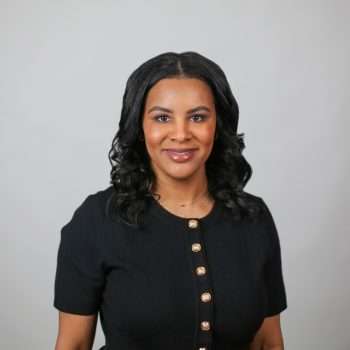A headshot of a person with black hair wearing a black shirt with buttons.