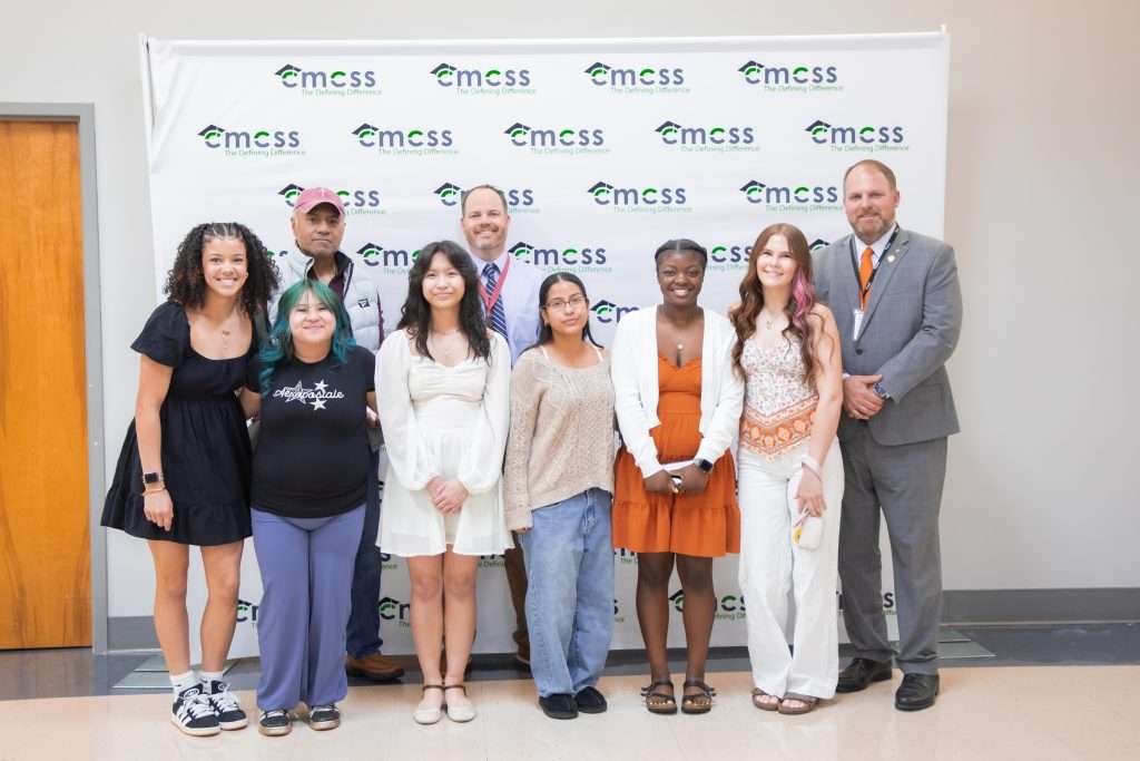 Group of people standing in front of a backdrop smiling with an award