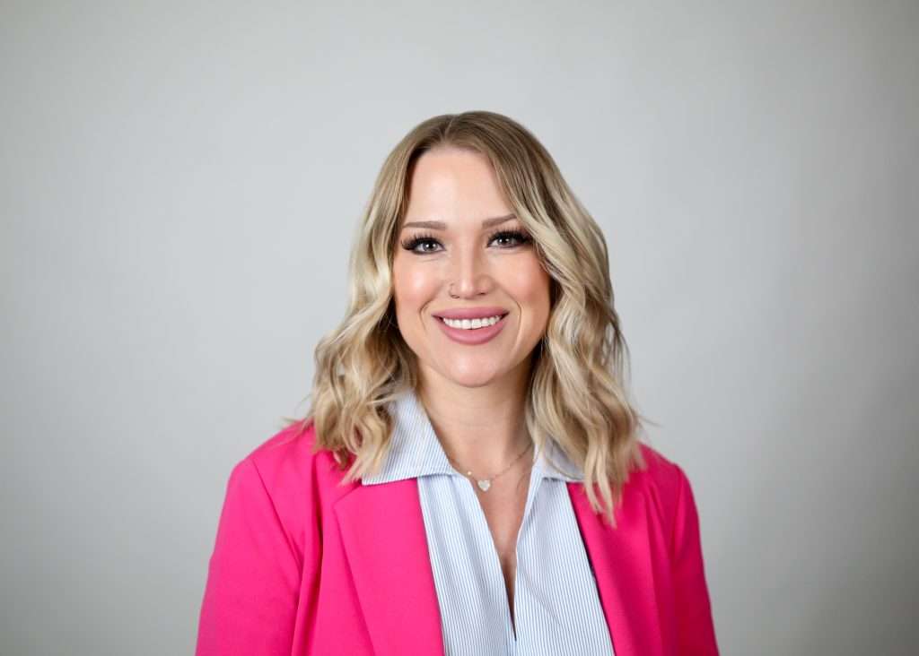 blonde woman in pink blazer smiling at camera