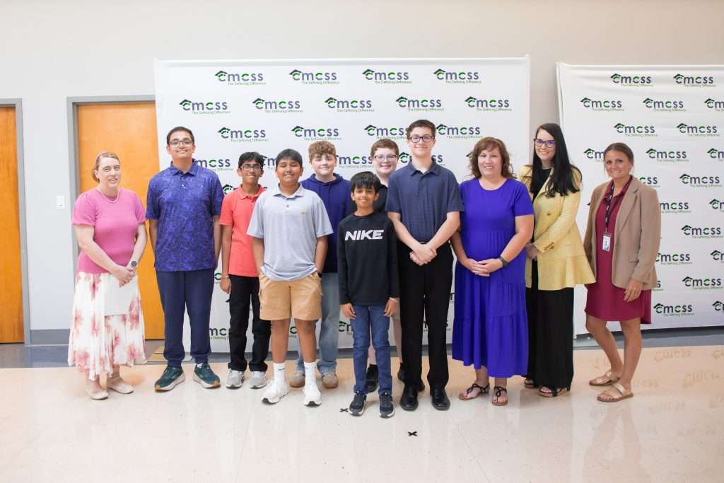 group of students and adults standing in front of backdrop
