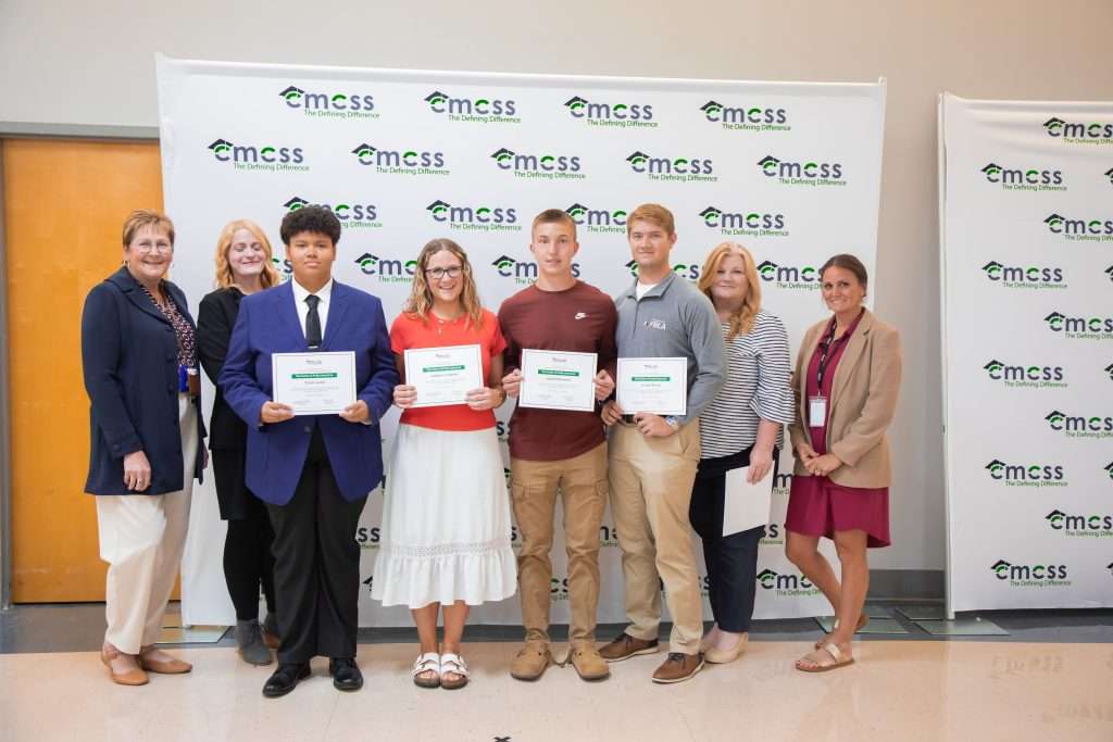 group of students and adults standing in front of backdrop