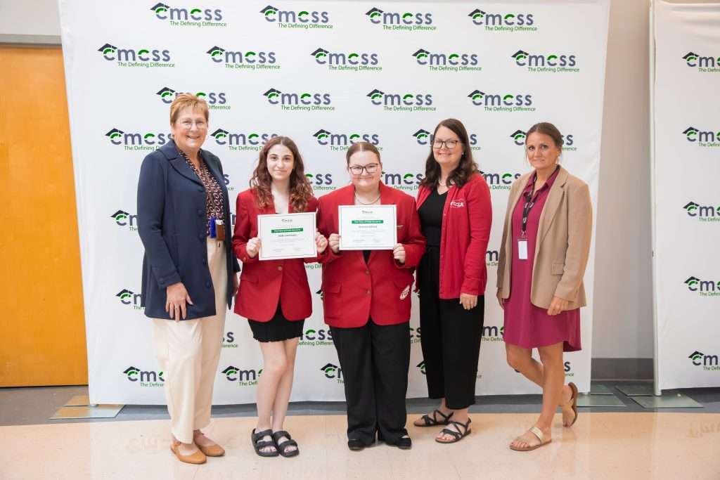group of students and adults standing in front of backdrop