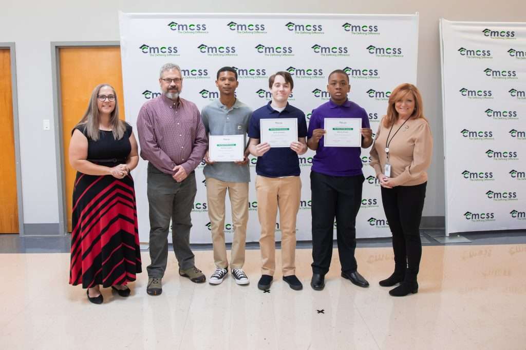 group of students and adults standing in front of backdrop