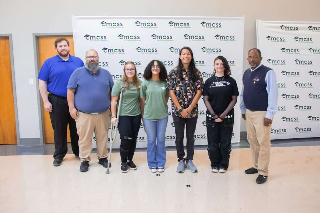 group of students and adults standing in front of backdrop