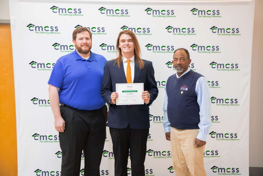 a student and adults standing in front of backdrop