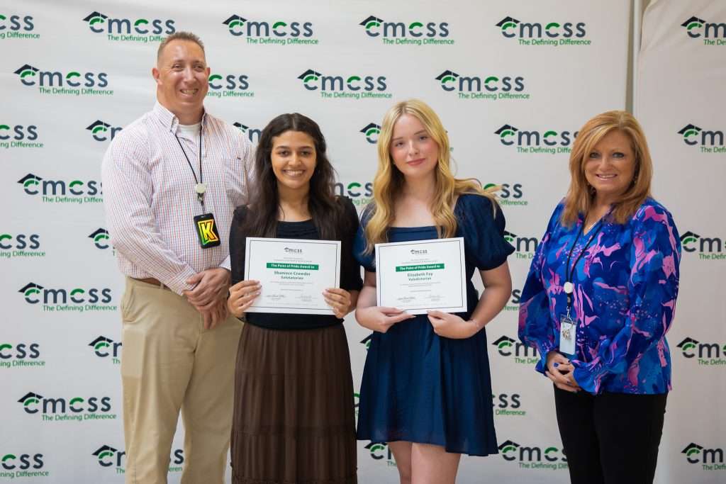 four people holding awards in front of backdrop