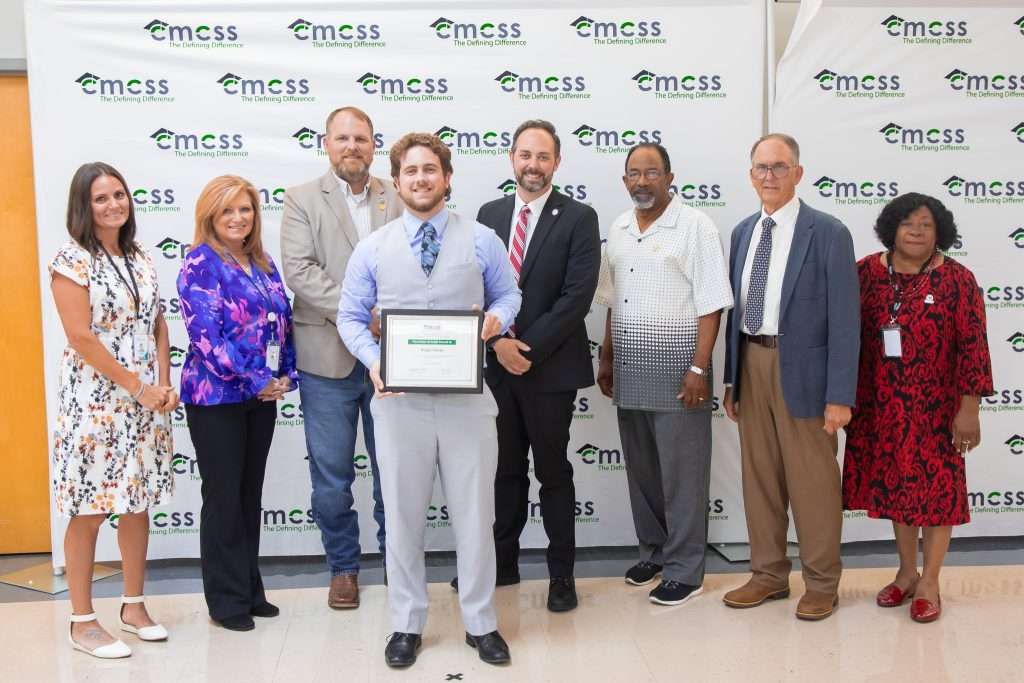 group of adults posing with a student holding an award