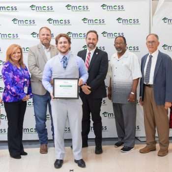 group of adults posing with a student holding an award