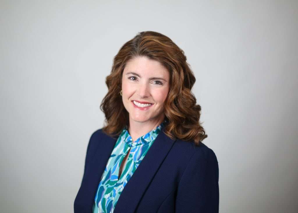 White woman with blue shirt and brown hair.