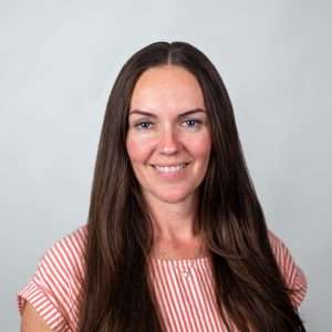 Headshot of Alicia Sims (woman with brown hair and white and red top)