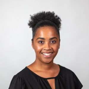 Headshot of Kianna Stanley (woman with dk brown hair and black top)