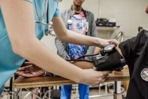 Photo of student take another student's blood pressure