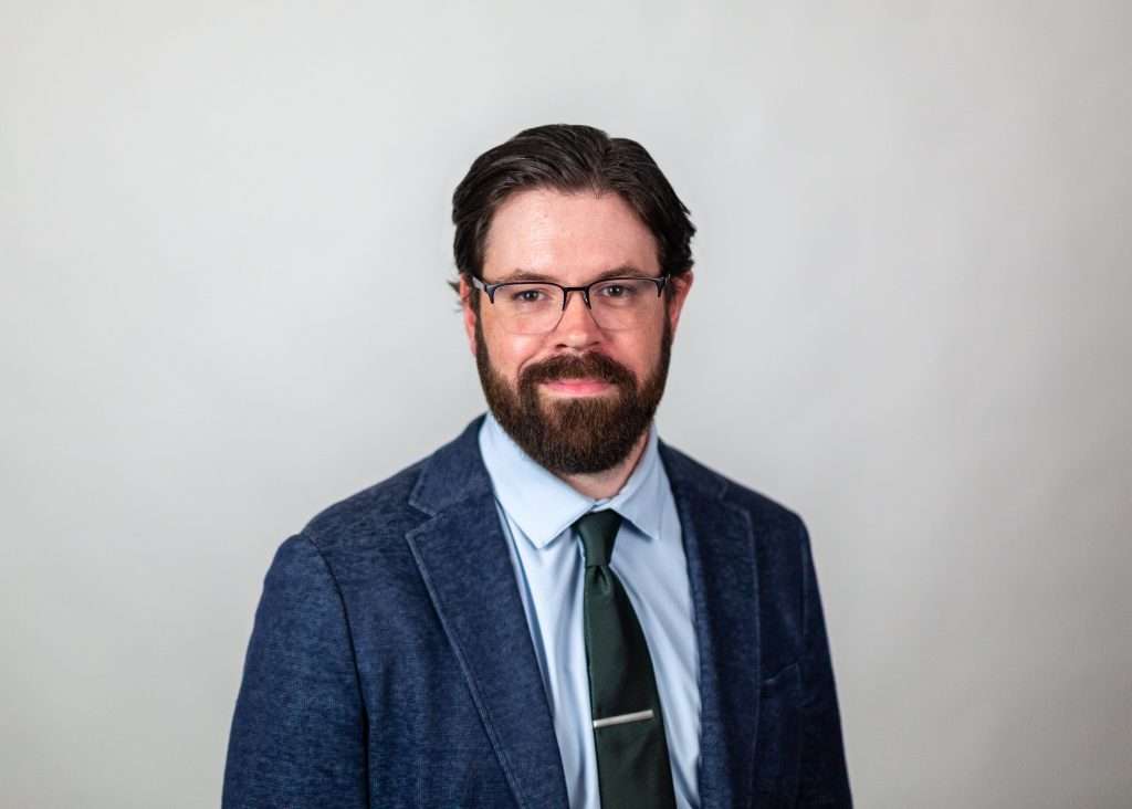 man in blue blazer wearing a tie and glasses